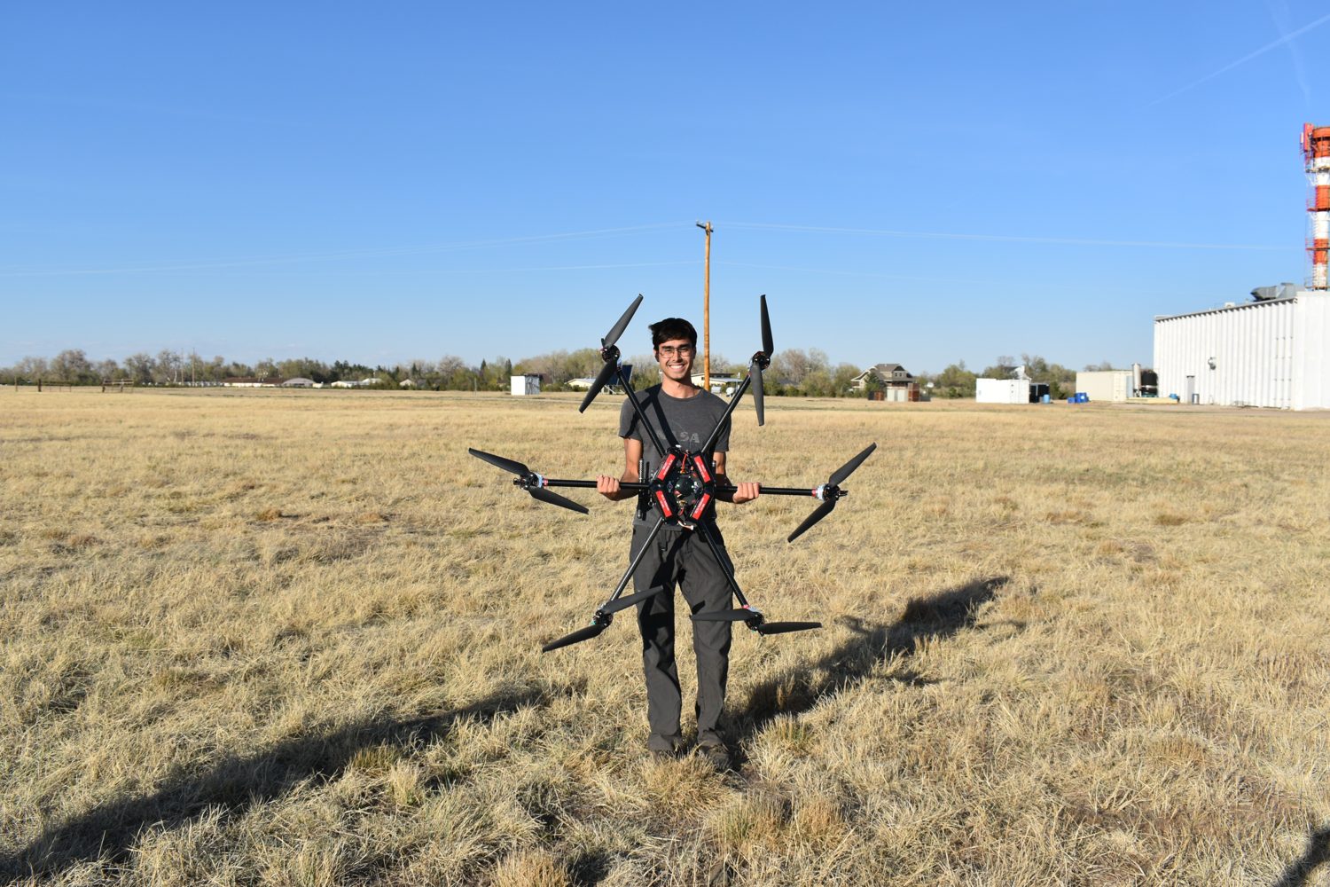 Wallace holding the hexacopter with all six arms extended in an open field