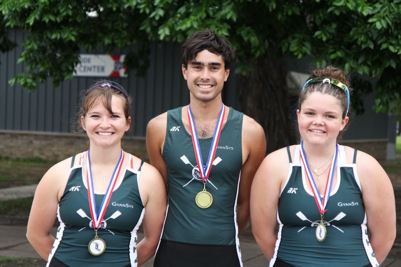 Wallace smiling with a gold medal between two teammates